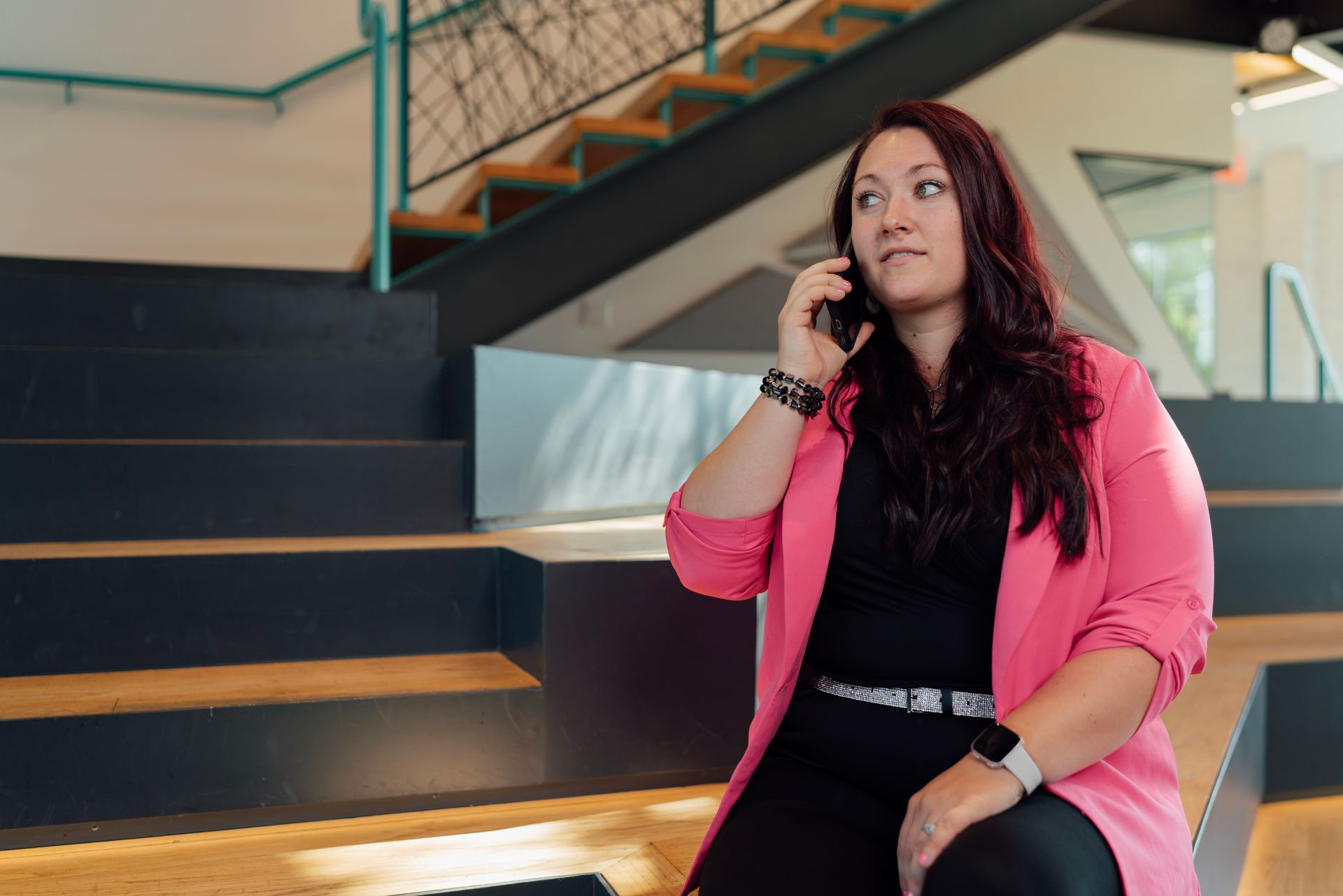 A woman is sitting on a staircase talking on a cell phone.