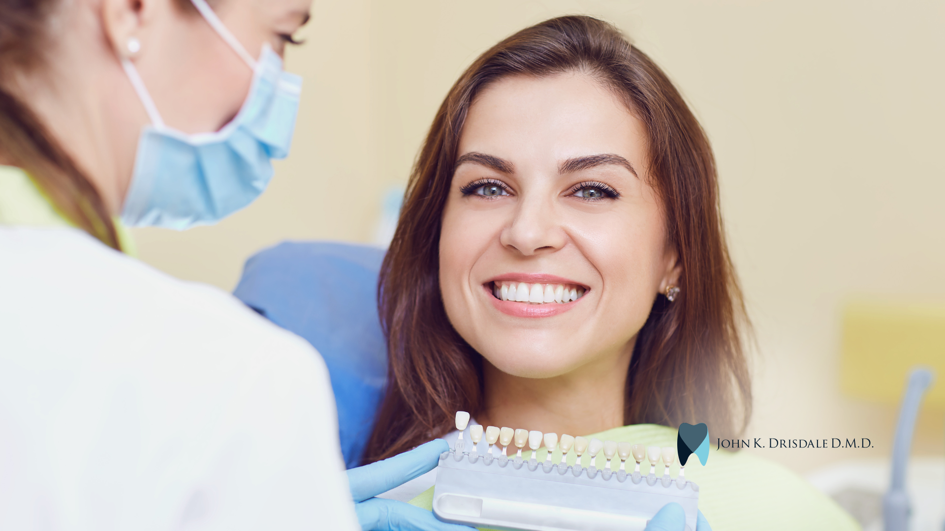 A woman is smiling while sitting in a dental chair while a dentist examines her teeth.