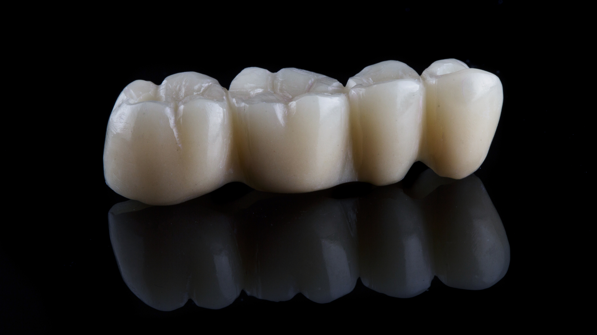 A close up of a dental bridge on a black surface.