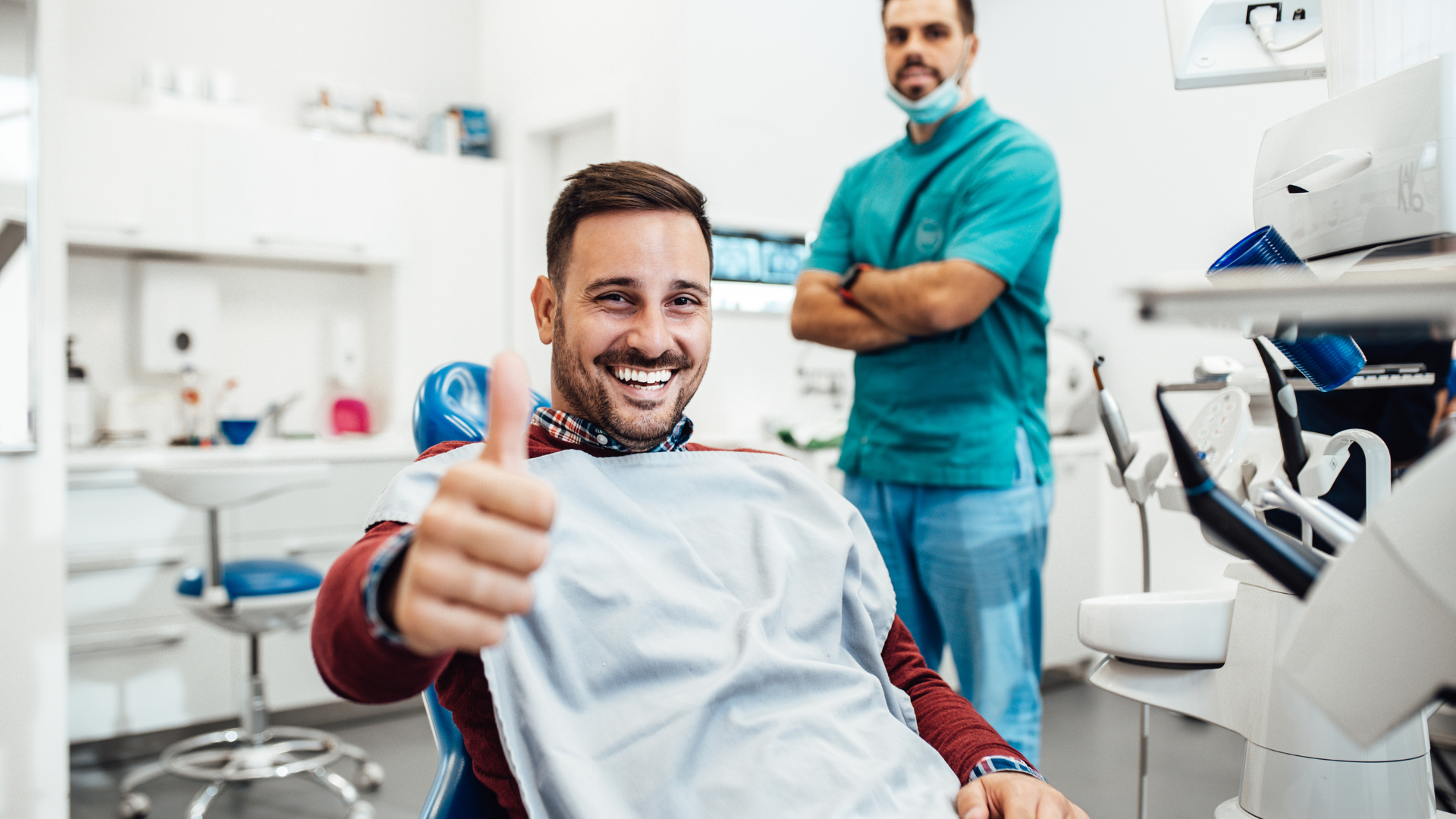 A man is giving a thumbs up while sitting in a dental chair.