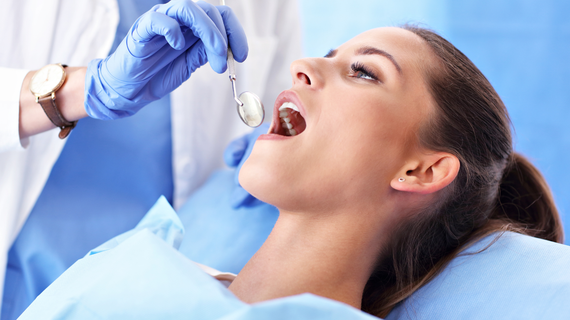 A woman is sitting in a dental chair holding a tooth in her hand.