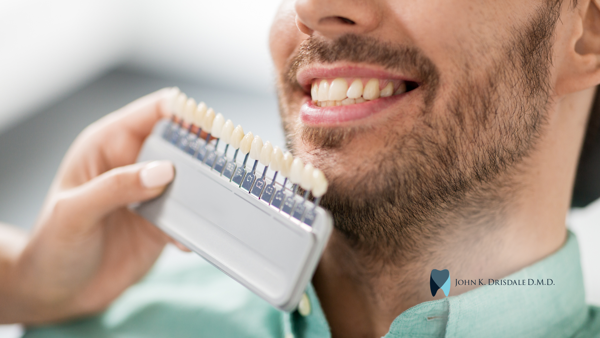 A man is holding a tooth color chart in front of his mouth.