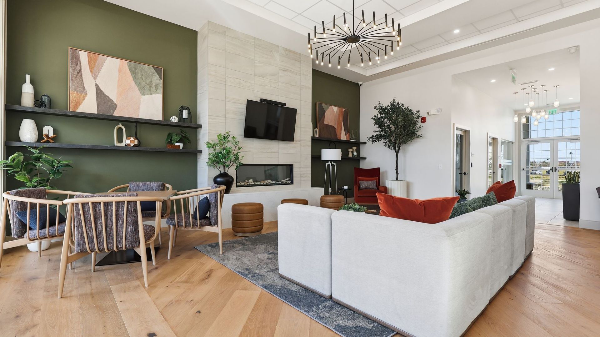 Modern living room with white sofa, fireplace, olive green accent wall, and wood flooring.