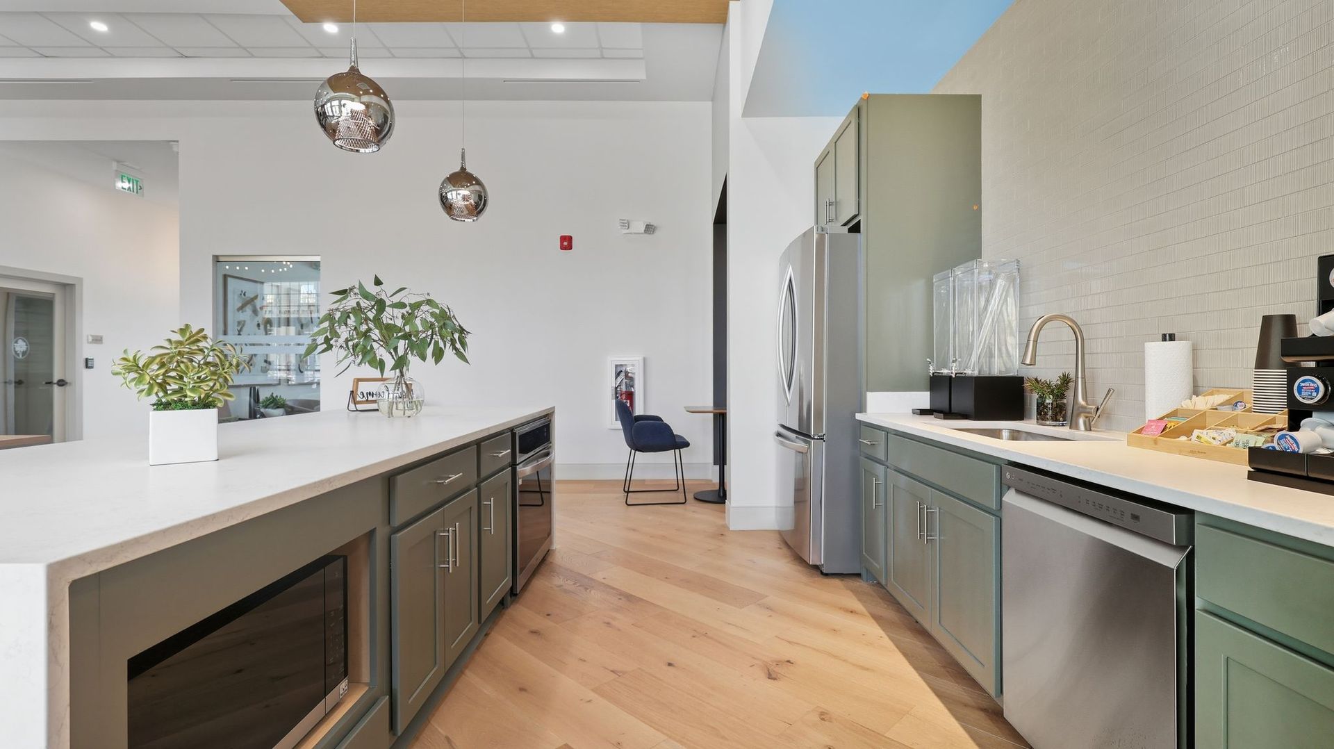 Kitchen with green cabinets, stainless steel appliances, and island with a microwave.