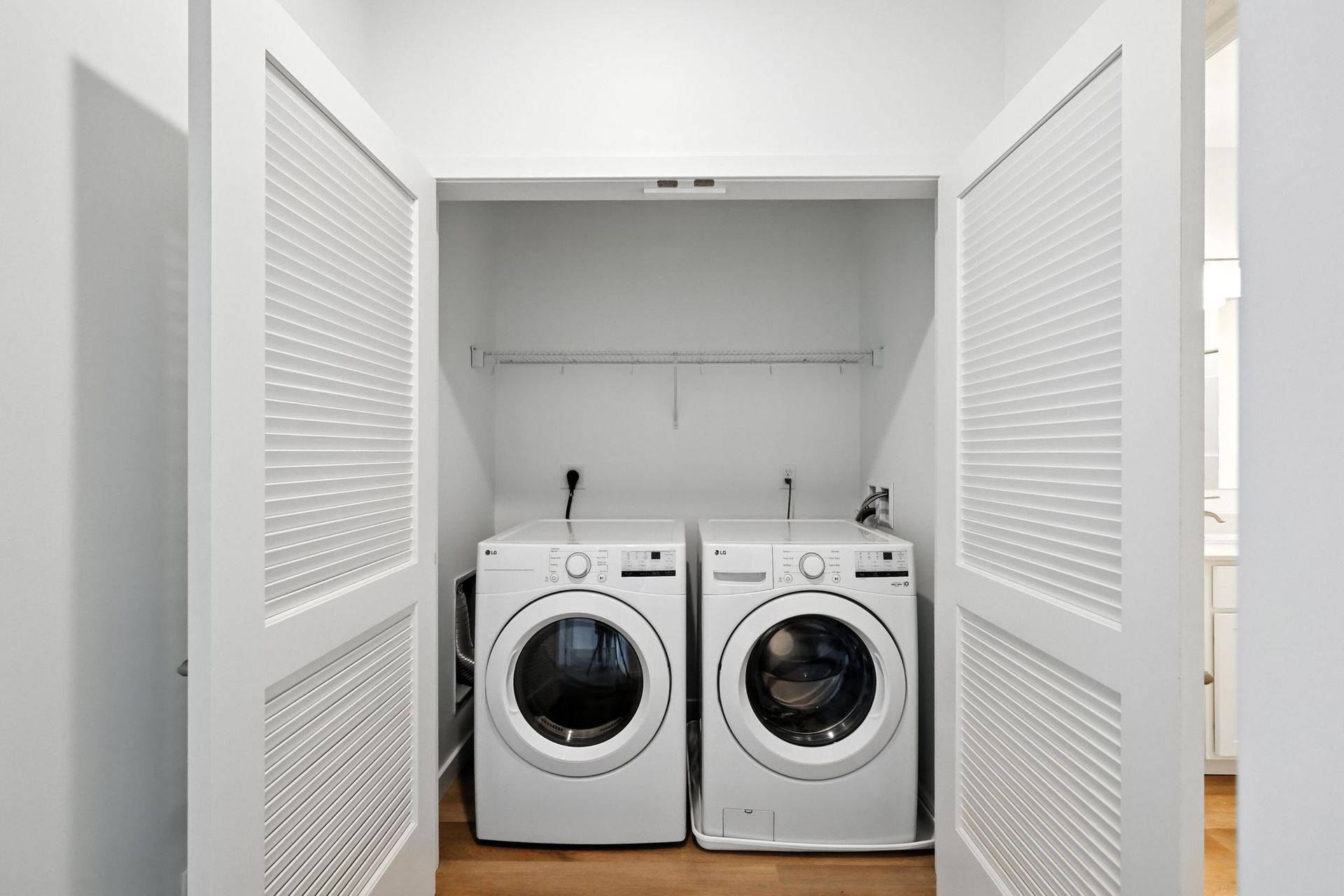 Laundry machines in a white closet with latticed doors.