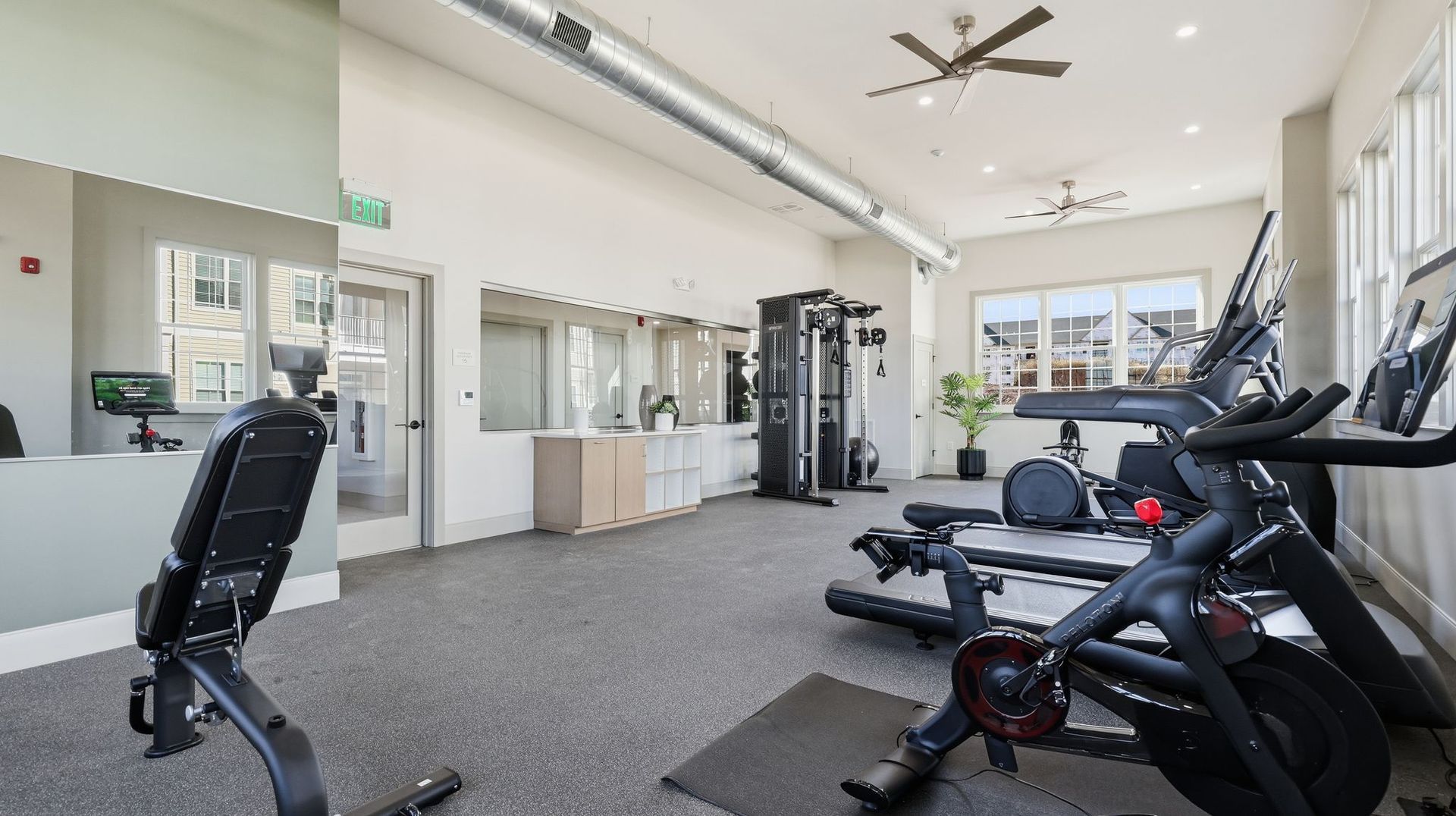 Gym interior with exercise equipment, including a Peloton bike and weight machine.