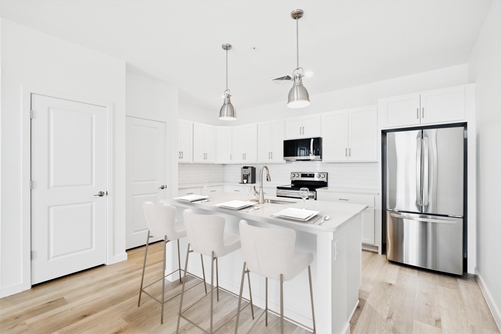 White kitchen with island, stainless steel appliances, and wood floors.