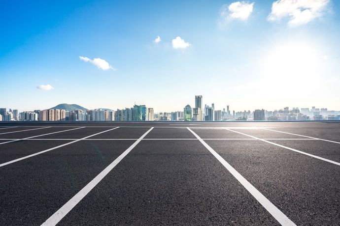 An empty parking lot with a city skyline in the background.