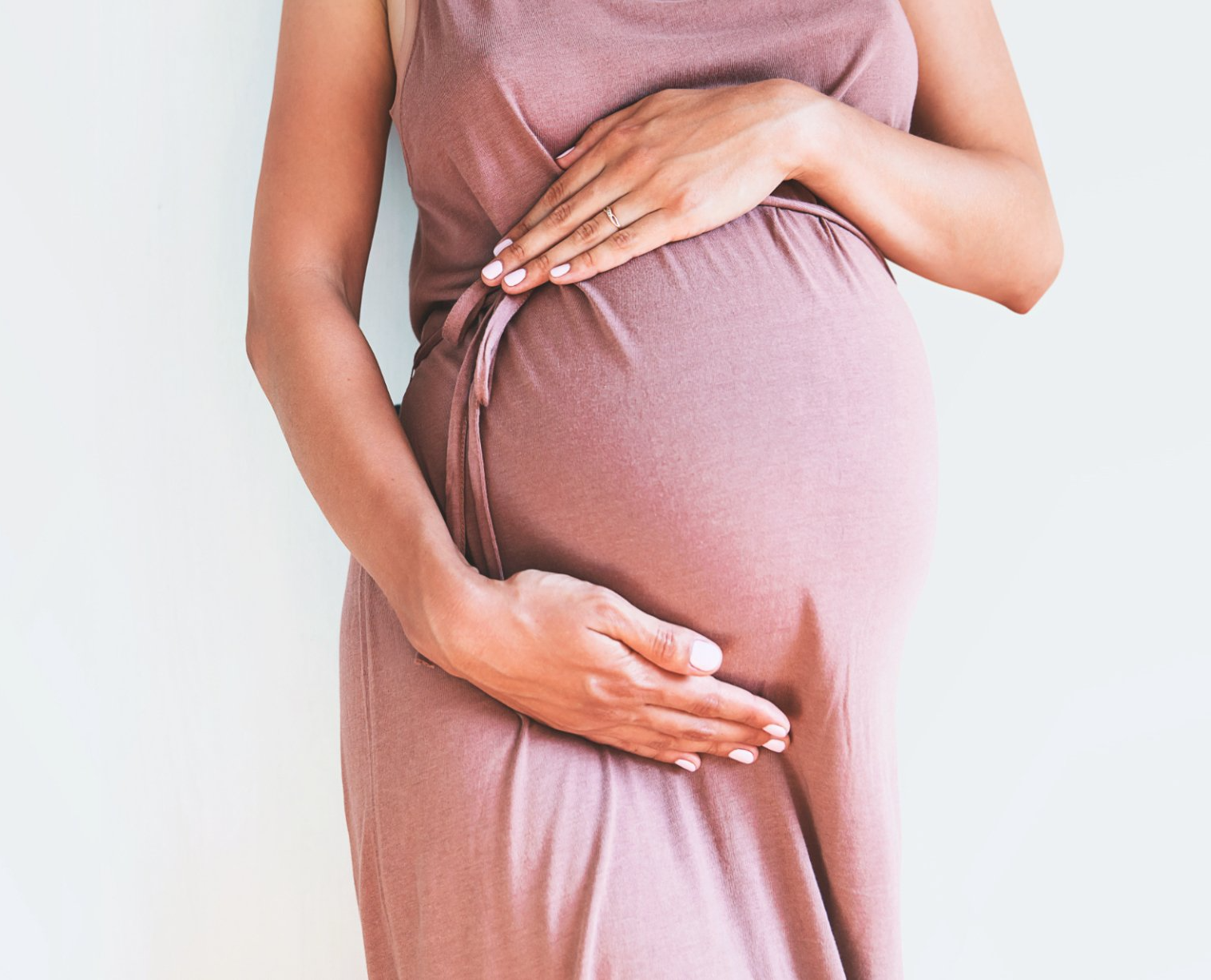 closeup of pregnant belly pink dress