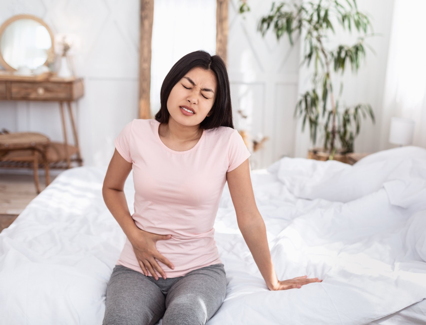 woman sitting on bed with pelvic pain