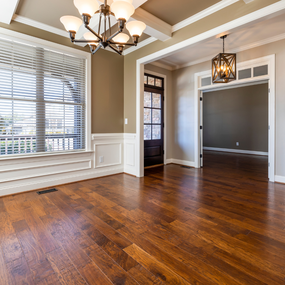 Empty dining room with dark hardwood floors, white wall trim, a chandelier, and a view into an adjacent room.