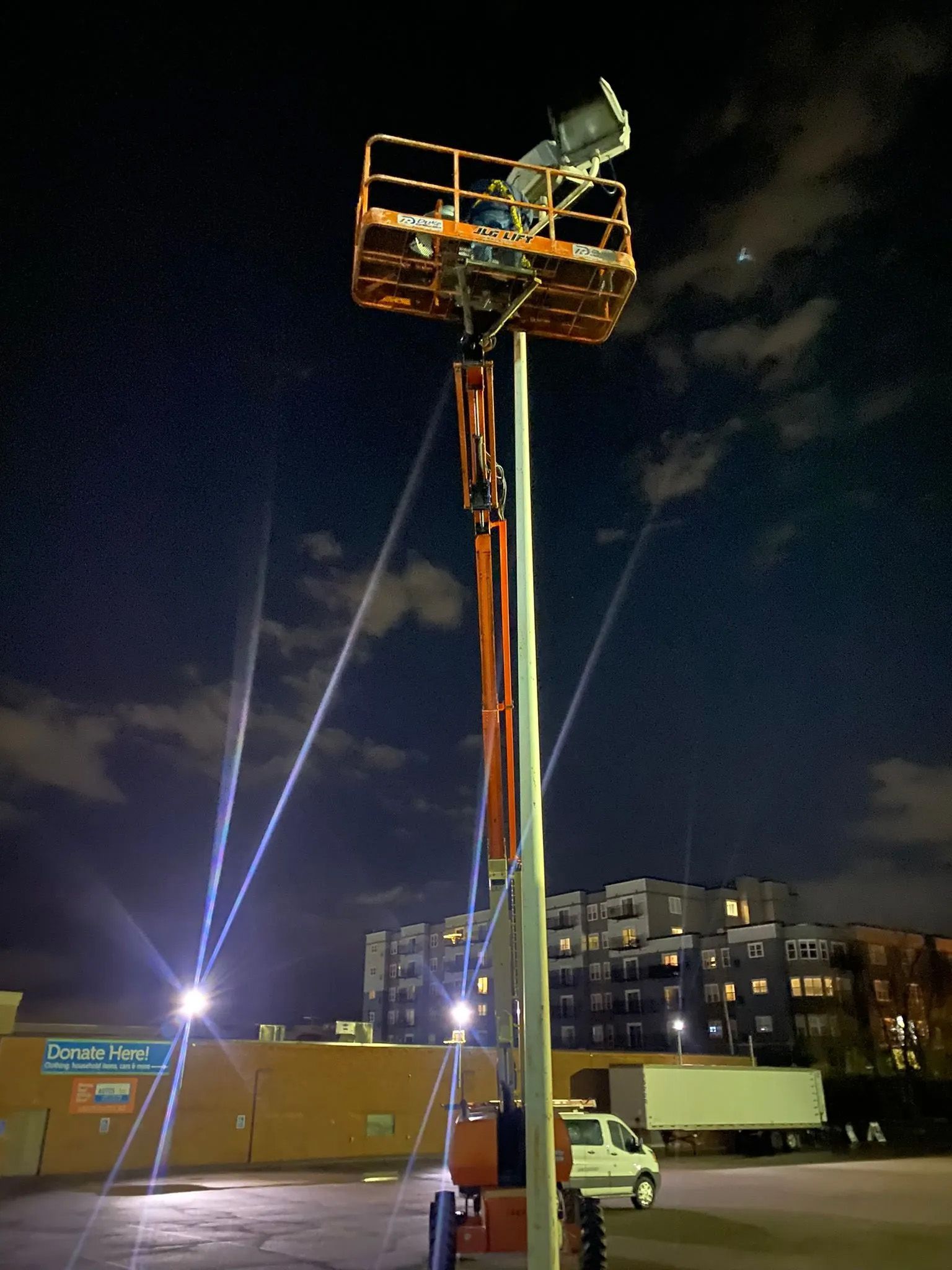 A crane is sitting on top of a tall pole at night