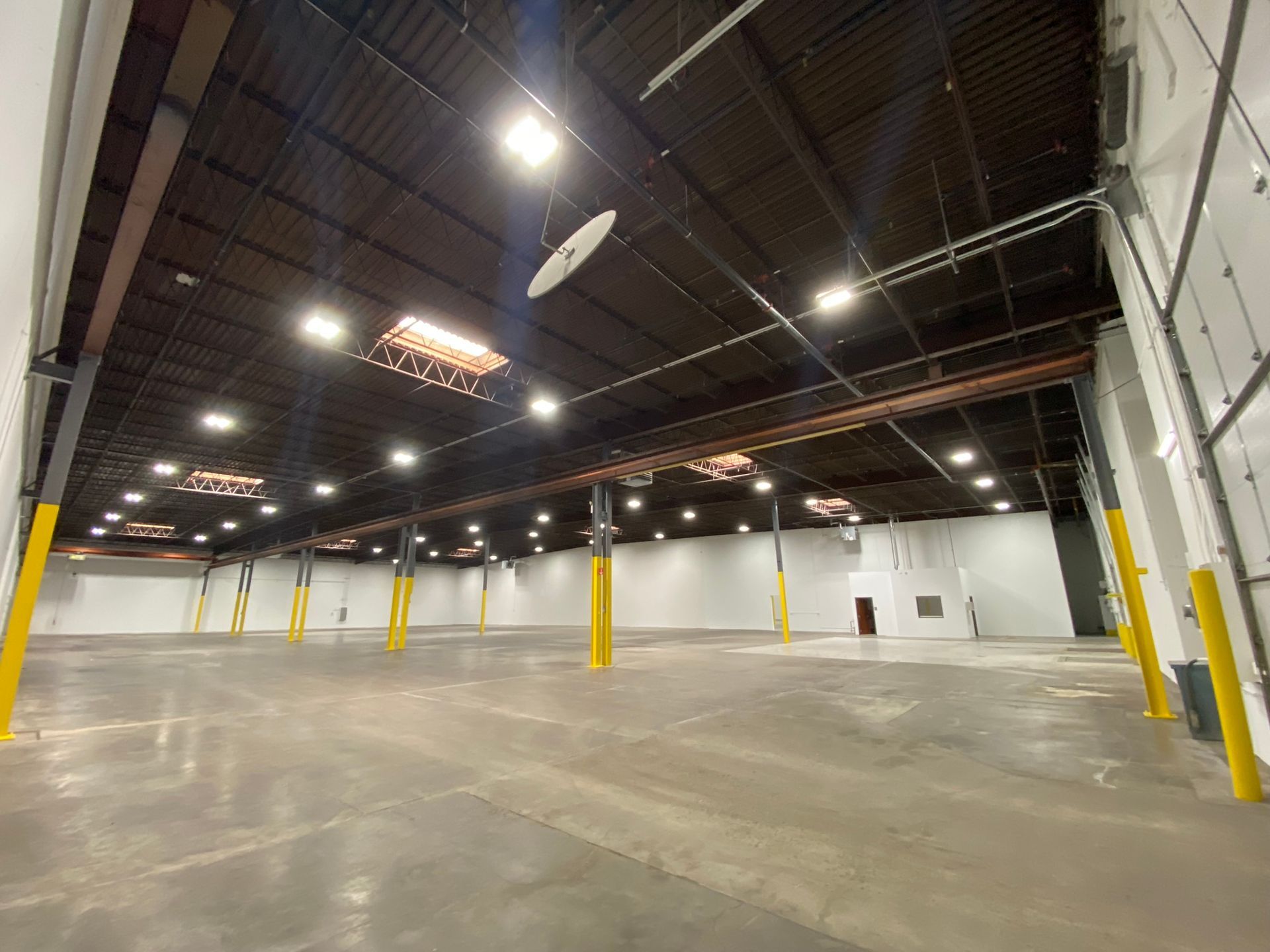 A large empty warehouse with a lot of lights on the ceiling.