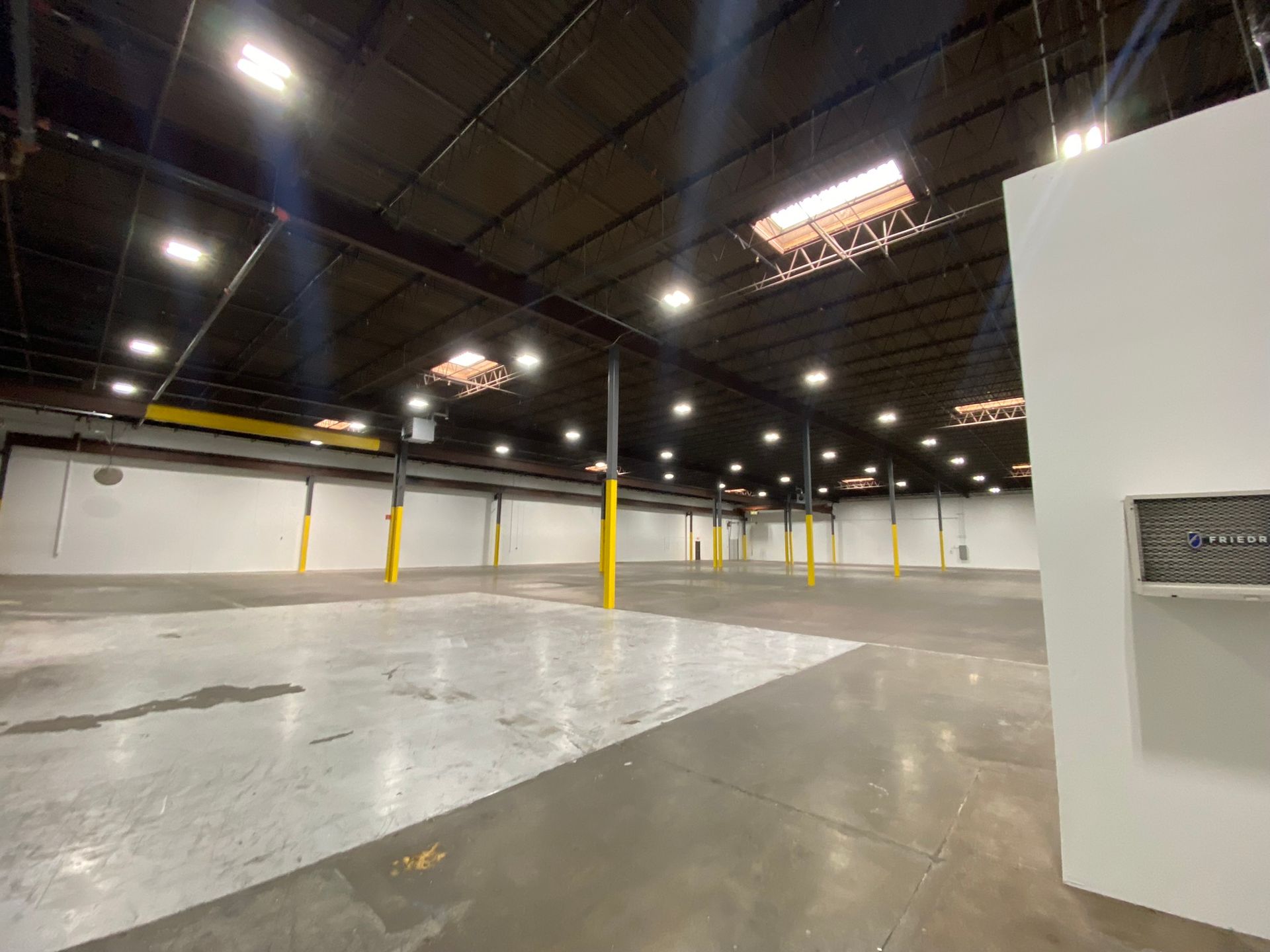 A large empty warehouse with a lot of lights on the ceiling.