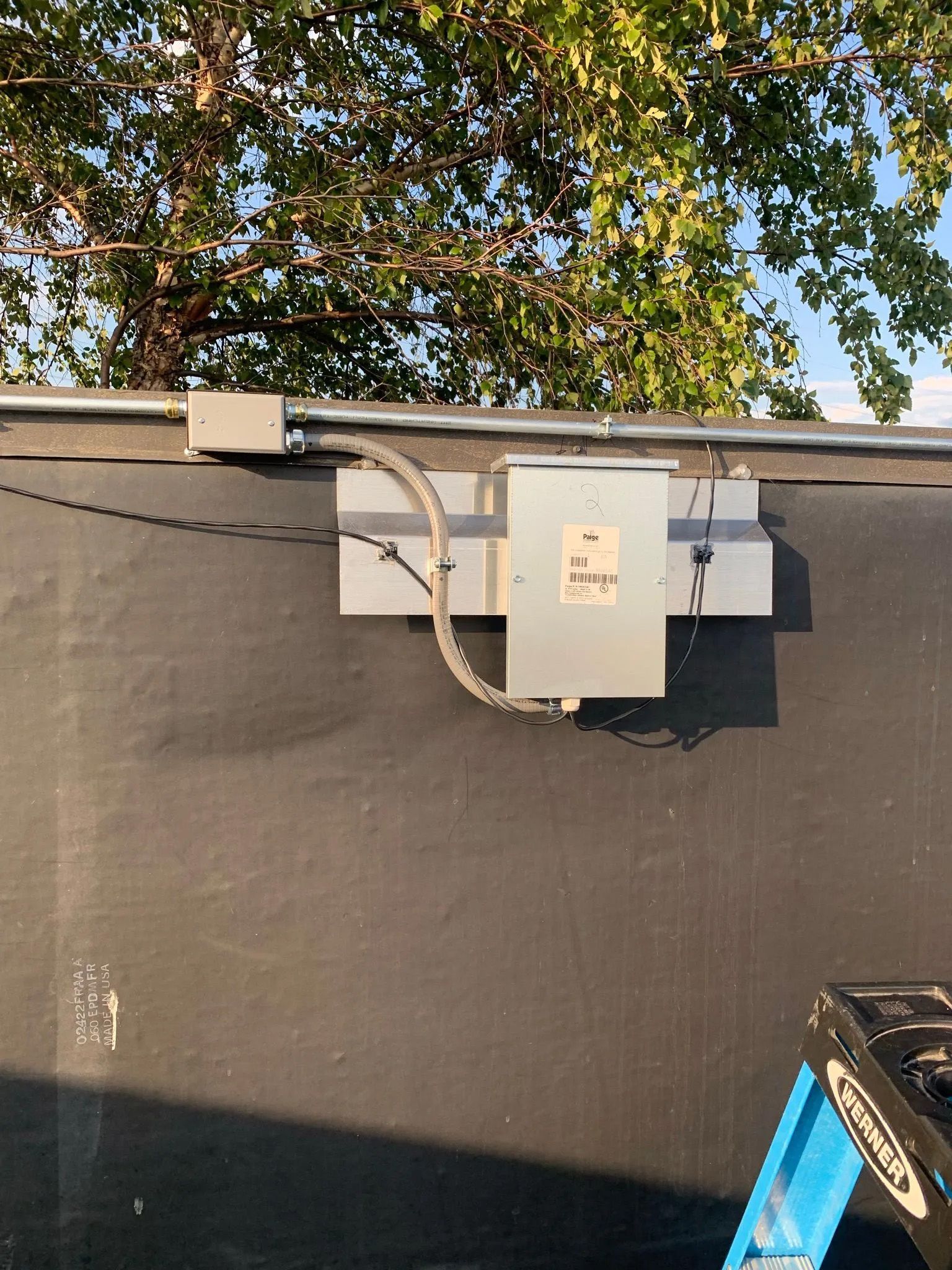 A ladder is sitting next to a box on the side of a building.