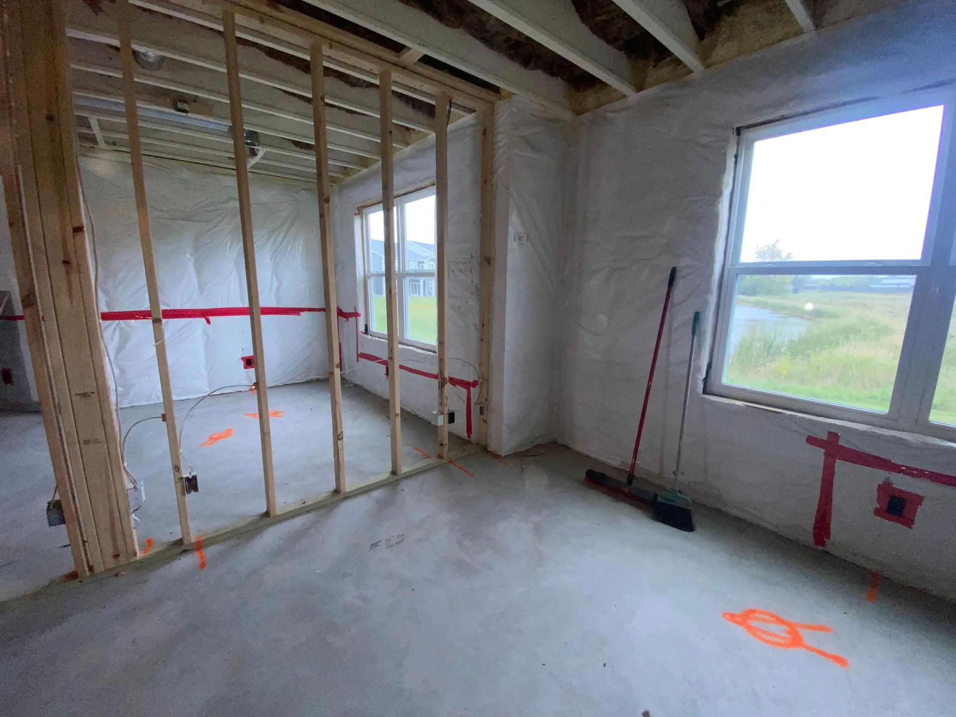 A room in a house under construction with a broom on the floor.