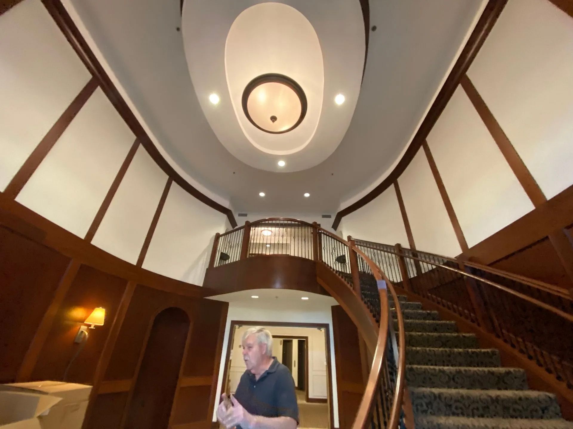 A man in a black shirt is standing in front of a spiral staircase