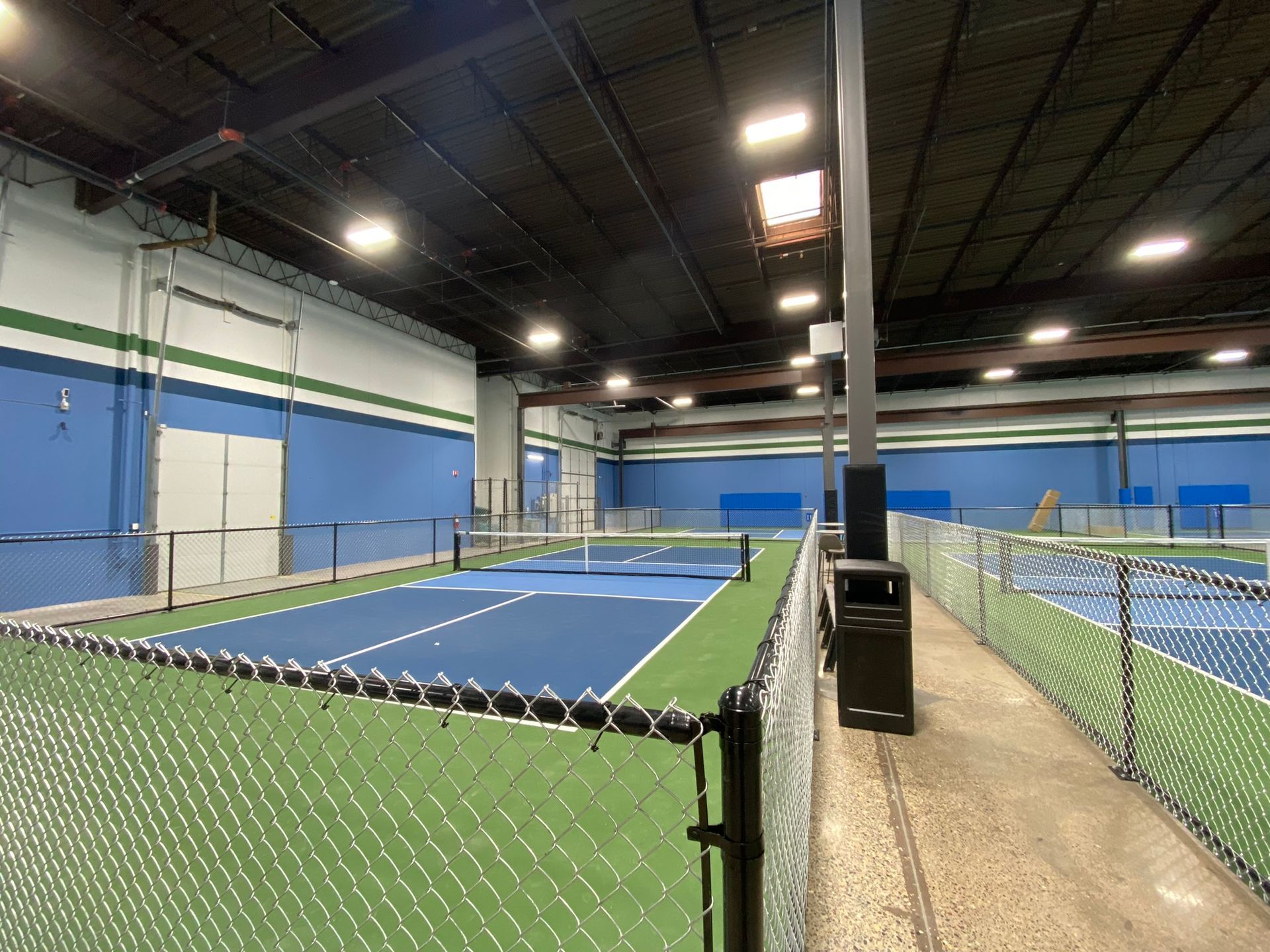 A tennis court inside of a building with a chain link fence