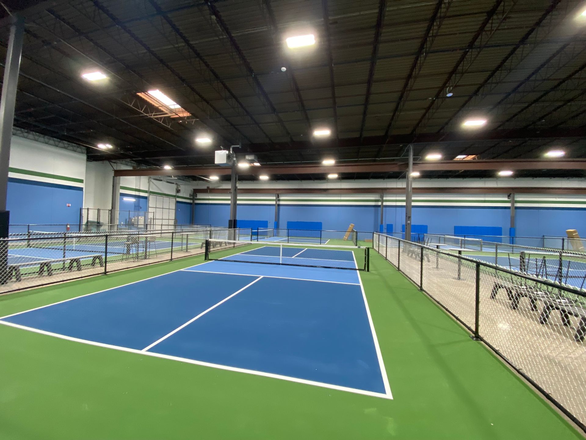 A large indoor tennis court with a fence around it.