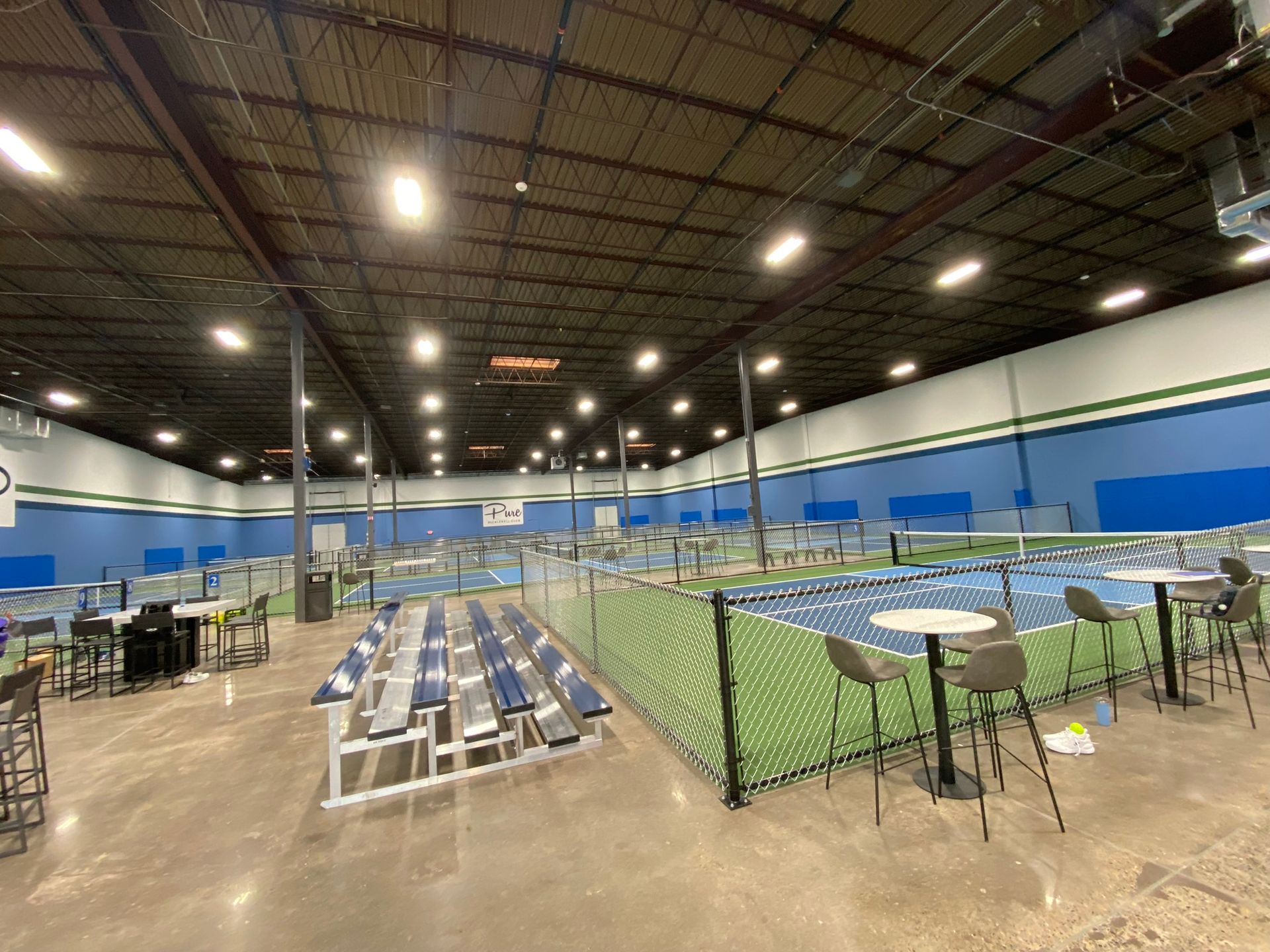 A large indoor tennis court with tables and chairs.