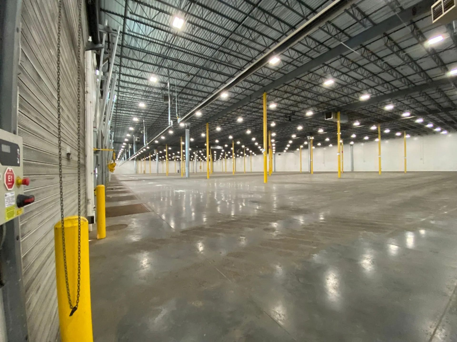 A large empty warehouse with lots of lights on the ceiling.