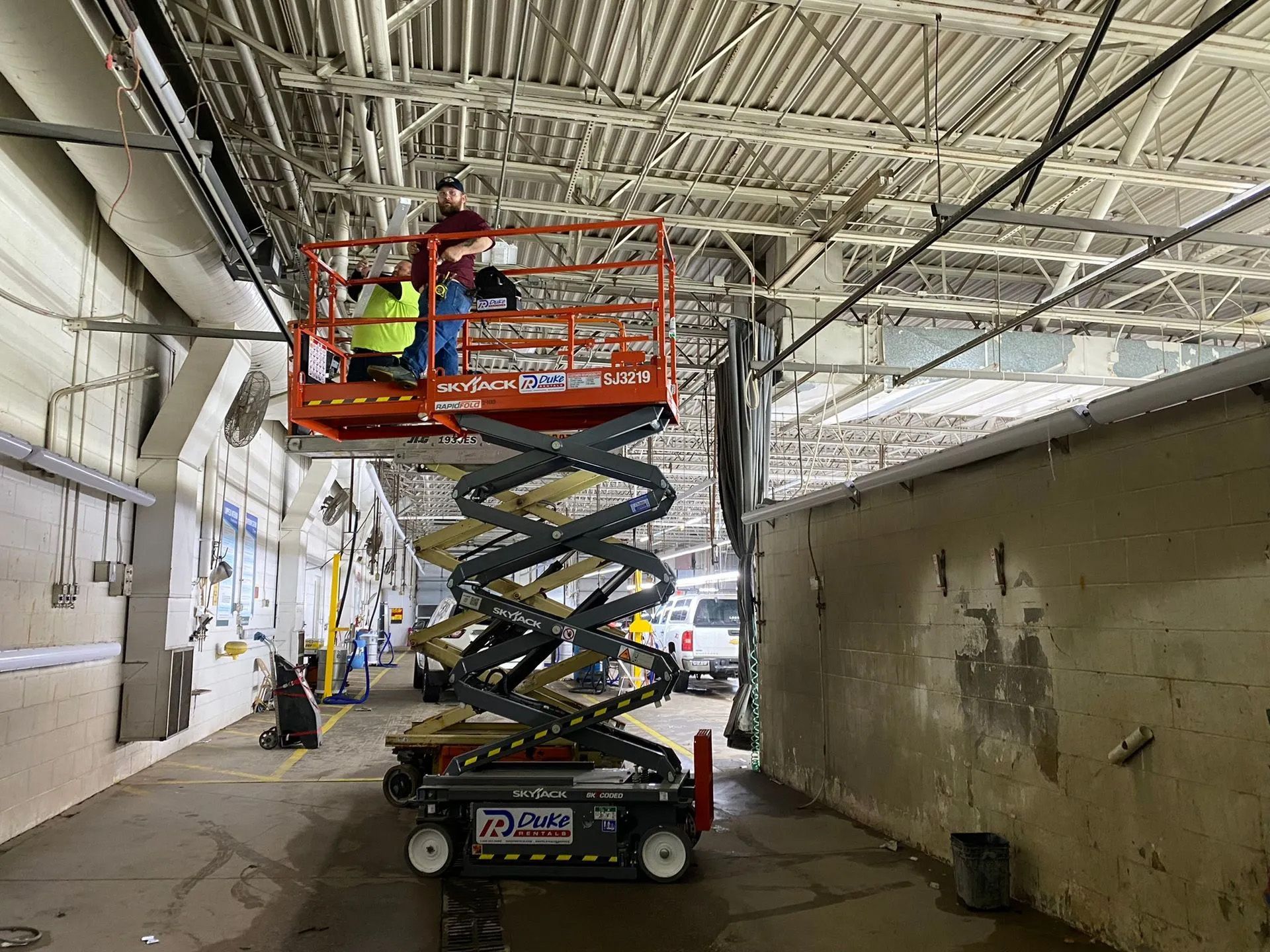 A man is sitting on a scissor lift in a building.