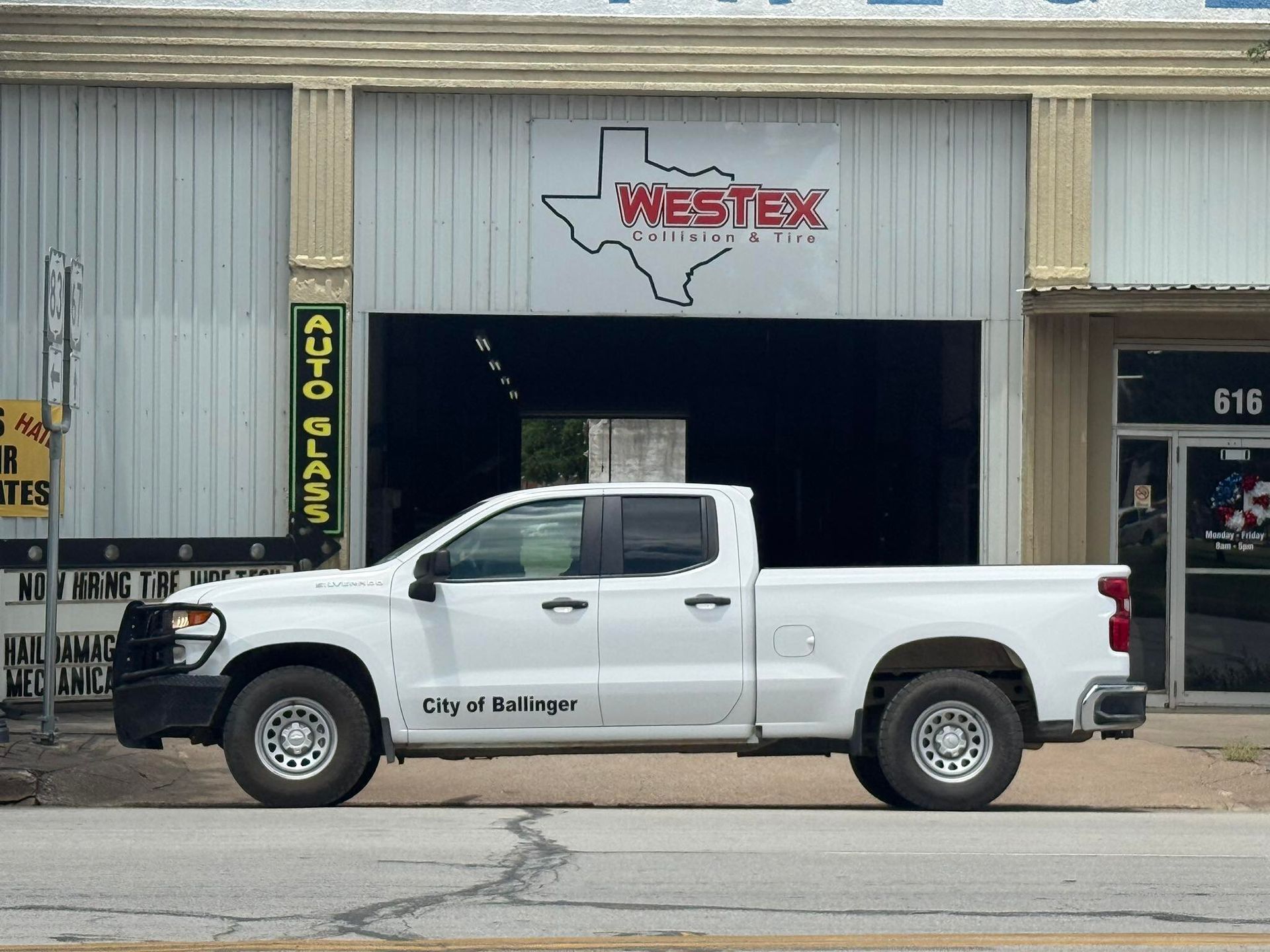 A white truck is parked in front of a westex auto parts store