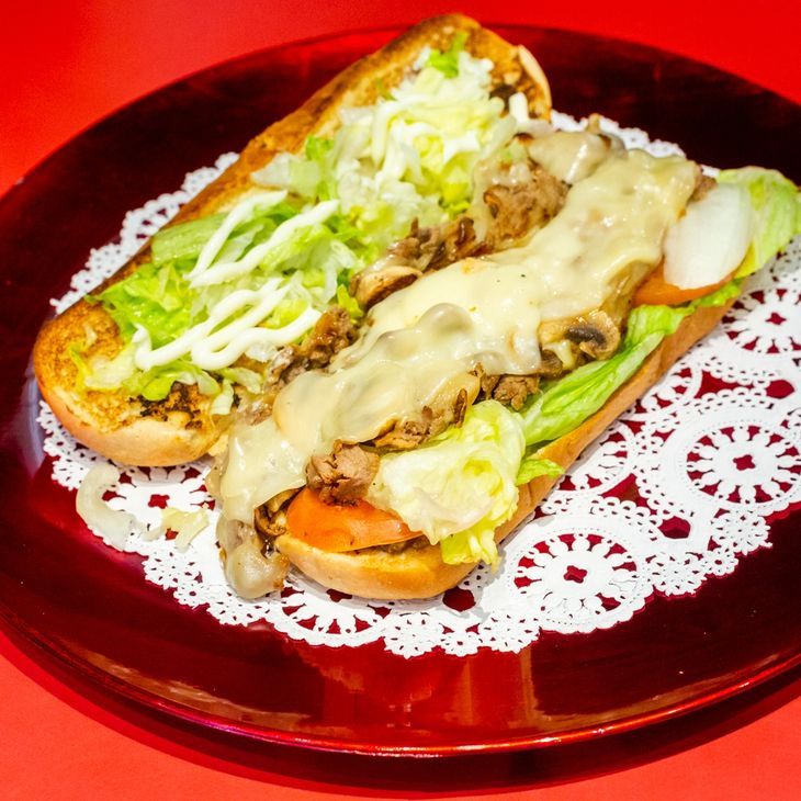 A sub sandwich with lettuce and cheese on a red plate