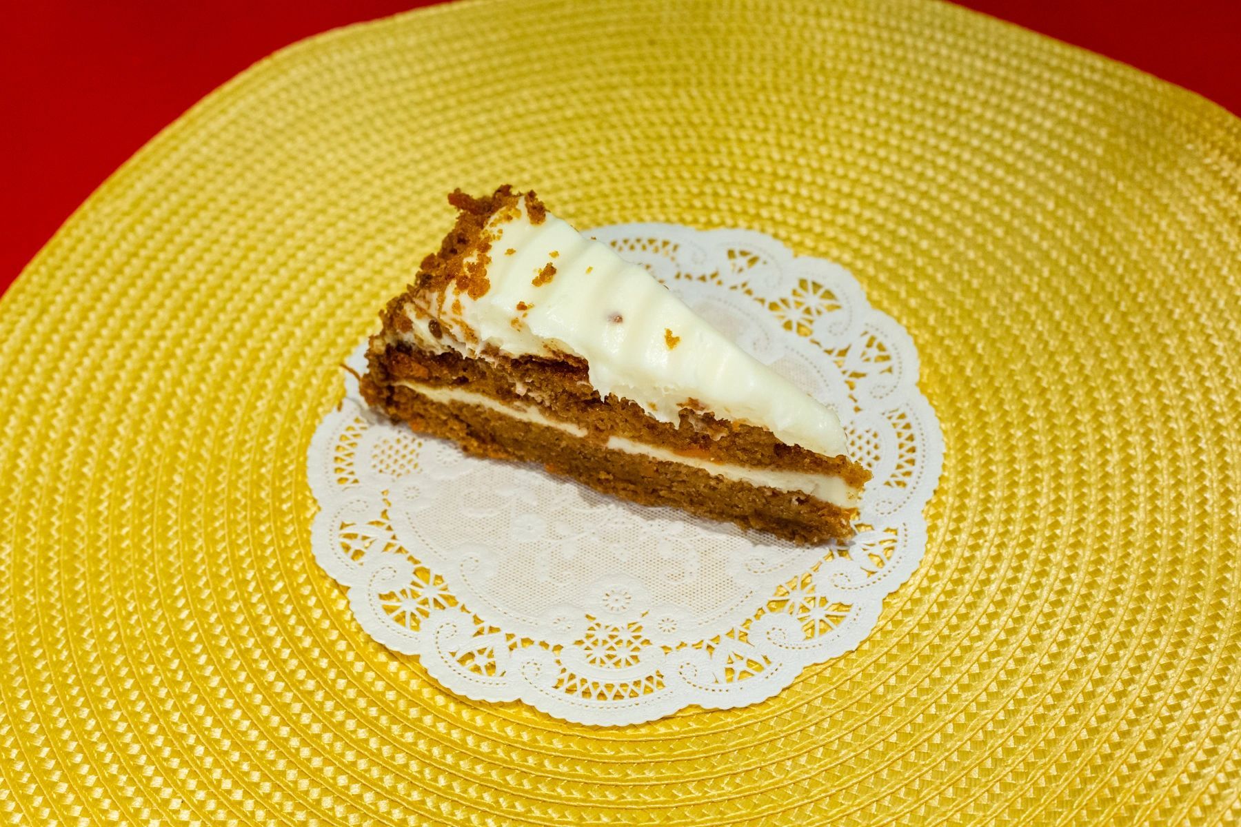 A slice of carrot cake on a yellow place mat