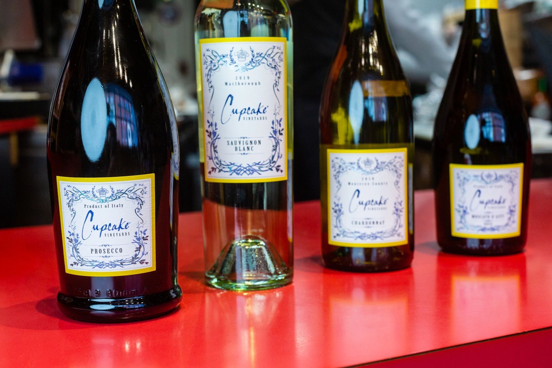 Four bottles of wine are sitting on a red table.