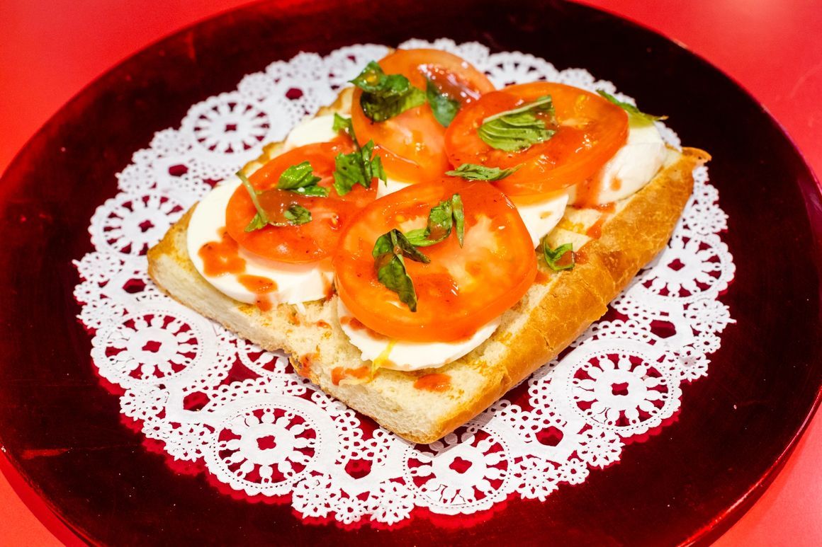 A sandwich with tomatoes and mozzarella on a red plate