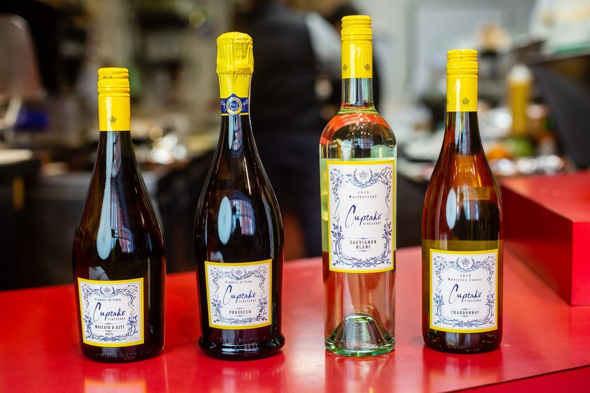 Four bottles of wine are sitting on a red table.