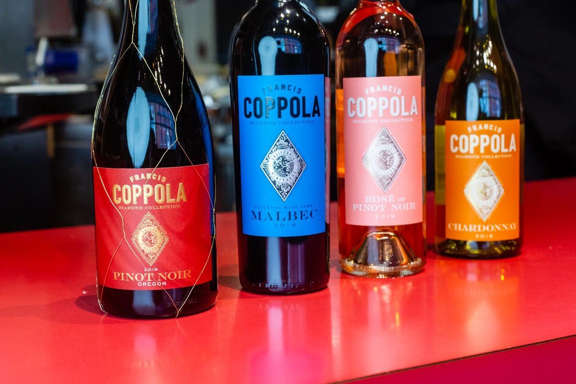 Four bottles of coppola wine are sitting on a red table.