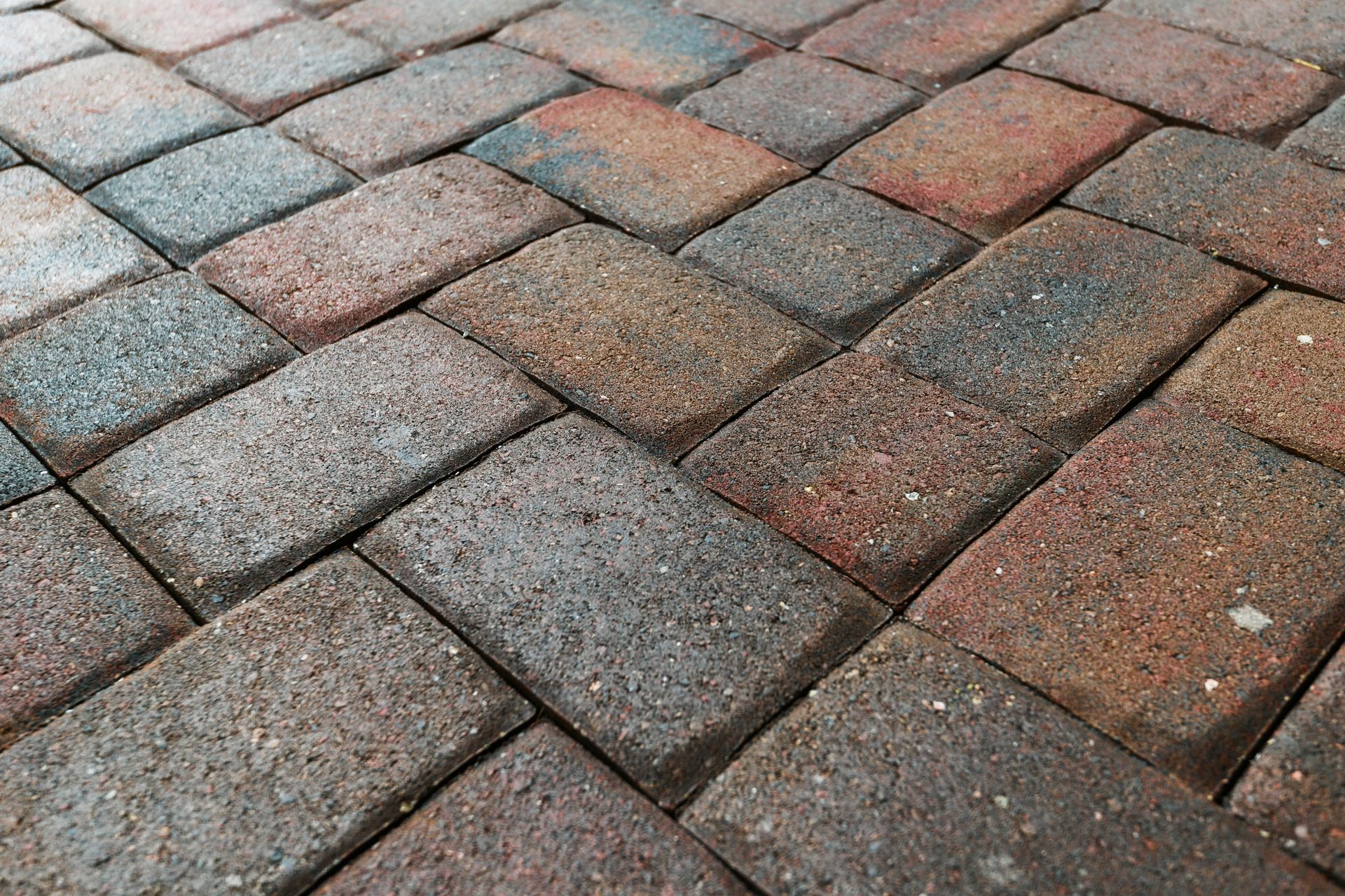 Herringbone pattern brickwork in various earthy tones: red, brown, and grey.