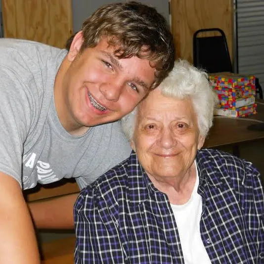 A young man and an older woman are posing for a picture