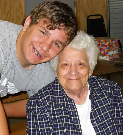 A young boy and an older woman are posing for a picture
