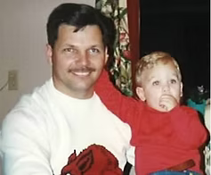 A man is holding a little boy in his arms.