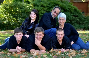 A family is posing for a picture while laying in the grass.