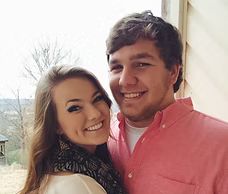 A man in a pink shirt is hugging a woman in a white sweater.