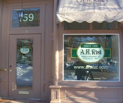 Exterior of A.H. Rist Insurance Agency building with sign, website, and awning at the entrance; snow in the background.
