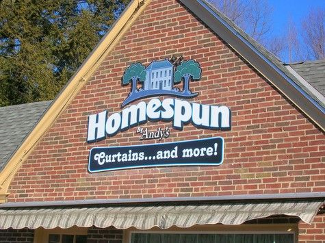 Homespun store sign on a brick building, featuring a house logo and the text 