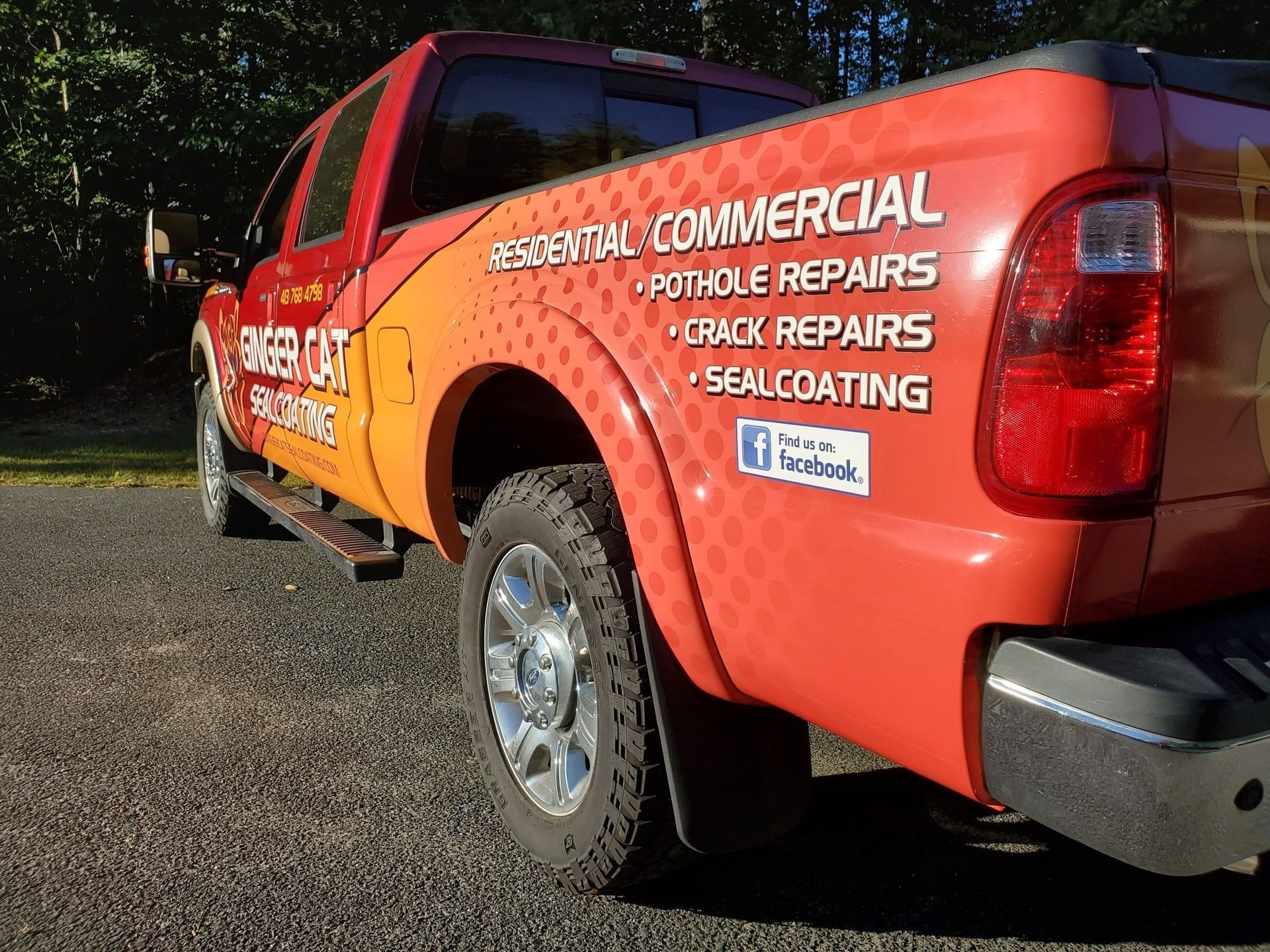 Red pickup truck with business logo advertising residential and commercial asphalt services.