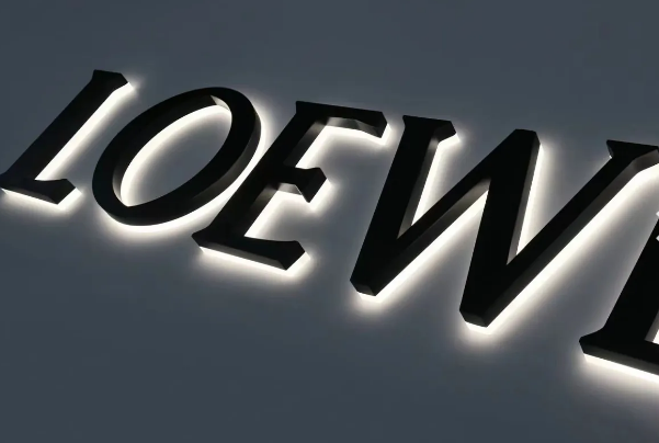 Loewe logo in black, backlit letters on a dark gray background.