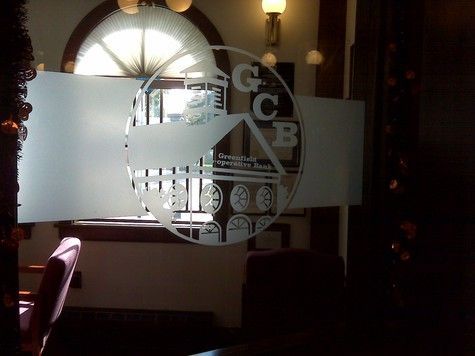 Frosted glass window with a bank logo, featuring initials and a globe design. Inside a dark interior.