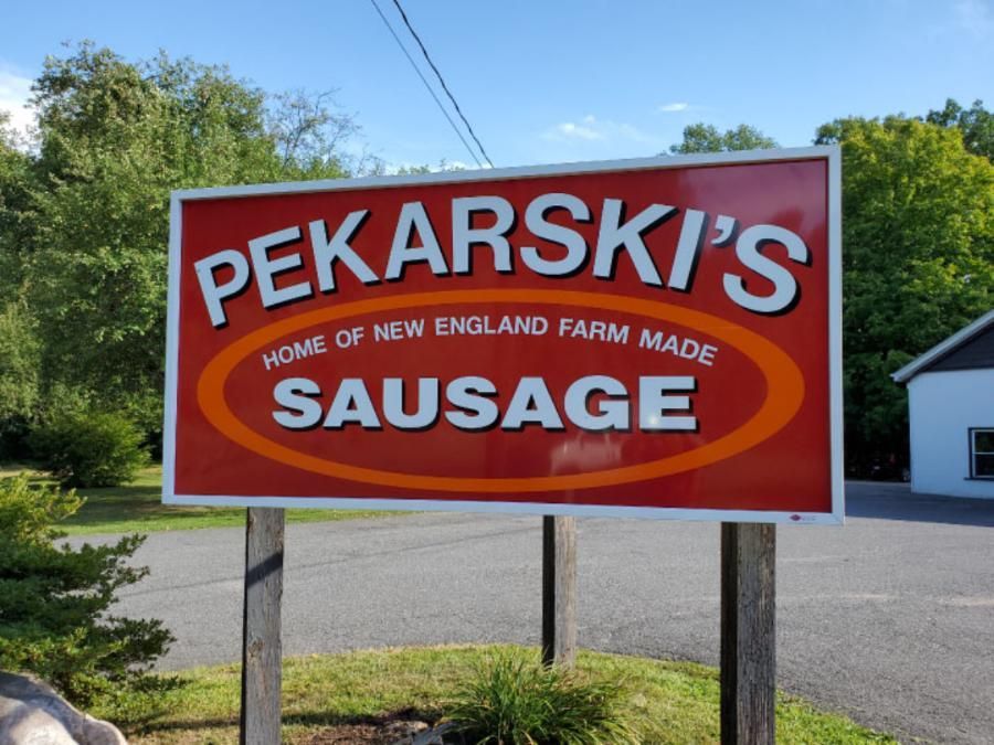 Sign for Pekarski's sausage, red and white with orange oval, says 