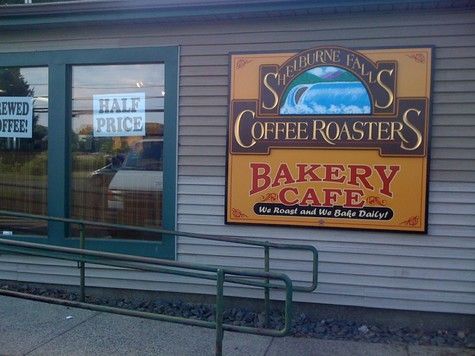 Sign for Shelburne Falls Coffee Roasters bakery cafe. Brown sign on a gray building. Green ramp.