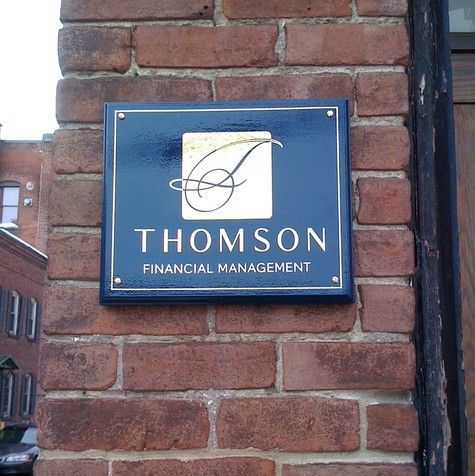 Sign for Thomson Financial Management on a brick wall.