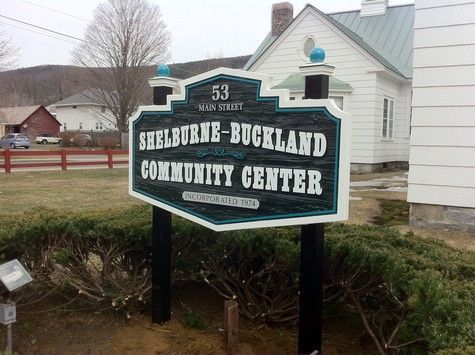 Sign for Shelburne-Buckland Community Center, 53 Main Street. Black, white, teal sign on a grassy area.