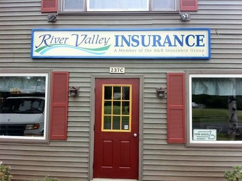 River Valley Insurance storefront with sign, red door, and shutters on a wood building.
