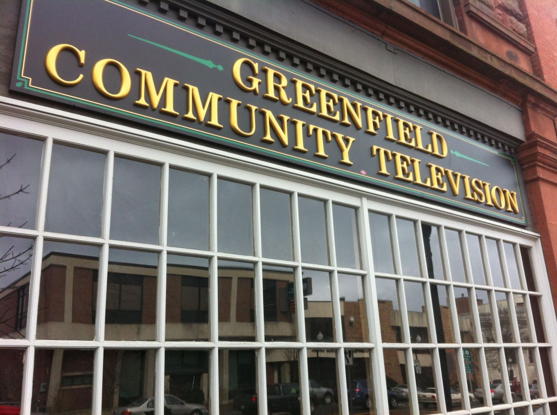 Sign for Greenfield Community Television above a storefront window.